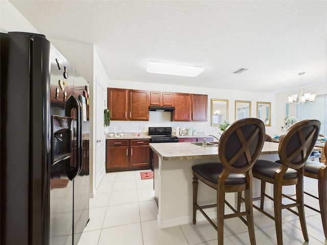5751 Lakeside Landings Blvd, Winter Haven, FL 33881 - kitchen with black appliances, under cabinet range hood, a chandelier, a breakfast bar area, and light tile patterned floors