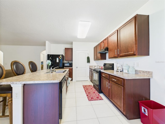 5751 Lakeside Landings Blvd, Winter Haven, FL 33881 - kitchen with black appliances, under cabinet range hood, a kitchen bar, light countertops, and light tile patterned flooring