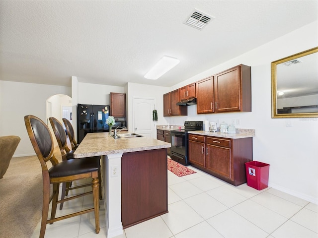 5751 Lakeside Landings Blvd, Winter Haven, FL 33881 - kitchen featuring black appliances, under cabinet range hood, light countertops, and a kitchen breakfast bar