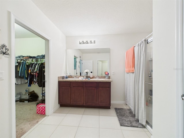5751 Lakeside Landings Blvd, Winter Haven, FL 33881 - bathroom with double vanity, a walk in closet, a shower with curtain, a textured ceiling, and tile patterned flooring