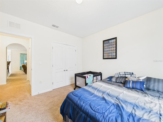 5751 Lakeside Landings Blvd, Winter Haven, FL 33881 - bedroom featuring arched walkways, light colored carpet, and a closet