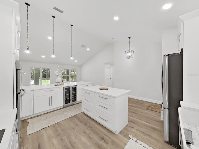 106 Corbett Rd, Lithia, FL 33547 - kitchen featuring wine cooler, freestanding refrigerator, light wood-type flooring, white cabinets, and decorative light fixtures