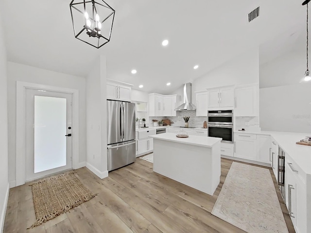106 Corbett Rd, Lithia, FL 33547 - kitchen featuring appliances with stainless steel finishes, wall chimney range hood, backsplash, light countertops, and lofted ceiling