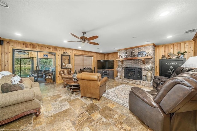 479 State Road 64 E, Zolfo Springs, FL 33890 - living area featuring wood walls, a ceiling fan, stone tile flooring, crown molding, and a brick fireplace