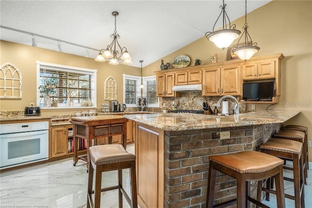 479 State Road 64 E, Zolfo Springs, FL 33890 - kitchen featuring oven, a breakfast bar area, light marble finish floors, tasteful backsplash, and light stone counters