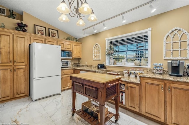 479 State Road 64 E, Zolfo Springs, FL 33890 - kitchen featuring freestanding refrigerator, stainless steel microwave, light marble finish floors, vaulted ceiling, and pendant lighting
