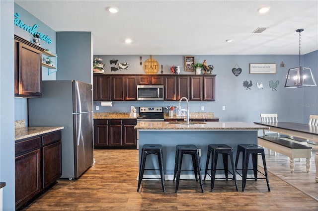 4662 Osprey Way, Winter Haven, FL 33881 - kitchen featuring stainless steel appliances, wood finished floors, pendant lighting, a kitchen bar, and recessed lighting