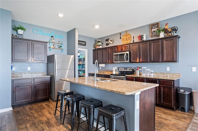 4662 Osprey Way, Winter Haven, FL 33881 - kitchen featuring appliances with stainless steel finishes, dark brown cabinetry, dark wood finished floors, a kitchen bar, and recessed lighting