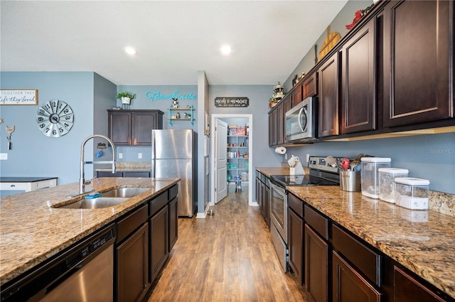 4662 Osprey Way, Winter Haven, FL 33881 - kitchen with appliances with stainless steel finishes, dark brown cabinets, light wood-style floors, light stone counters, and recessed lighting