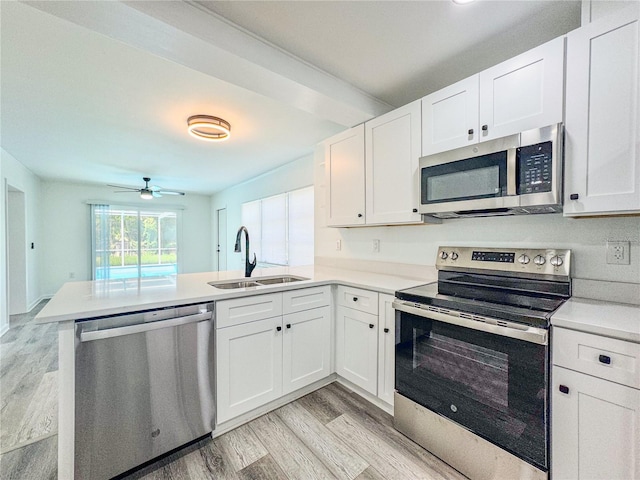 938 Glenwood Ave, Sebring, FL 33870 - kitchen featuring stainless steel appliances, a peninsula, light wood-style floors, light countertops, and white cabinetry