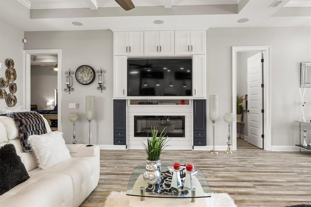 545 Pond Cypress Ct, Auburndale, FL 33823 - living room featuring a ceiling fan, wood finished floors, crown molding, a glass covered fireplace, and beamed ceiling