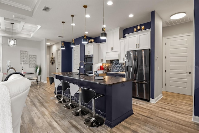 545 Pond Cypress Ct, Auburndale, FL 33823 - kitchen with black appliances, dark countertops, custom exhaust hood, an island with sink, and light wood finished floors