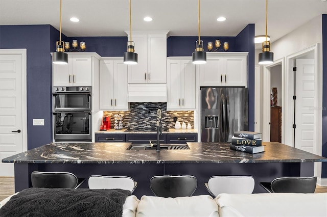 545 Pond Cypress Ct, Auburndale, FL 33823 - kitchen featuring appliances with stainless steel finishes, a kitchen bar, backsplash, white cabinets, and a kitchen island with sink