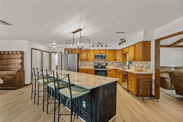 914 Mangham Rd, Babson Park, FL 33827 - kitchen featuring appliances with stainless steel finishes, light wood finished floors, light stone counters, decorative backsplash, and a textured ceiling
