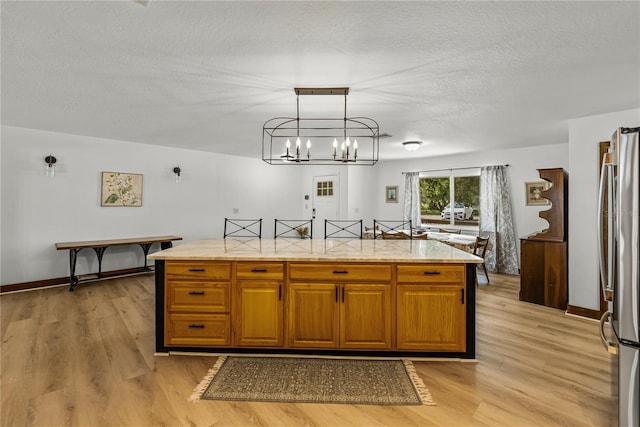 914 Mangham Rd, Babson Park, FL 33827 - kitchen with freestanding refrigerator, light wood-type flooring, light stone counters, a chandelier, and a textured ceiling