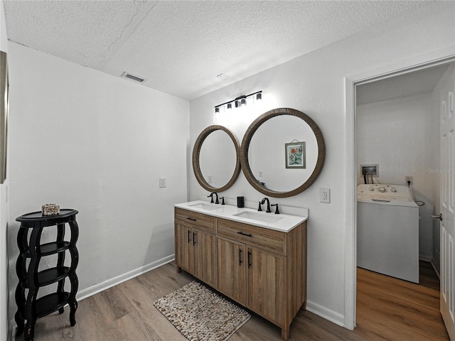 914 Mangham Rd, Babson Park, FL 33827 - bathroom with washer / dryer, wood finished floors, a textured ceiling, and double vanity