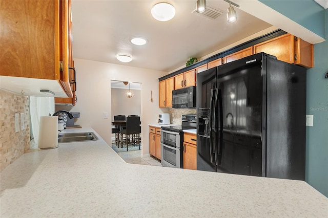 611 Caddy Dr, Kissimmee, FL 34759 - kitchen featuring black appliances, backsplash, light countertops, light tile patterned flooring, and brown cabinetry