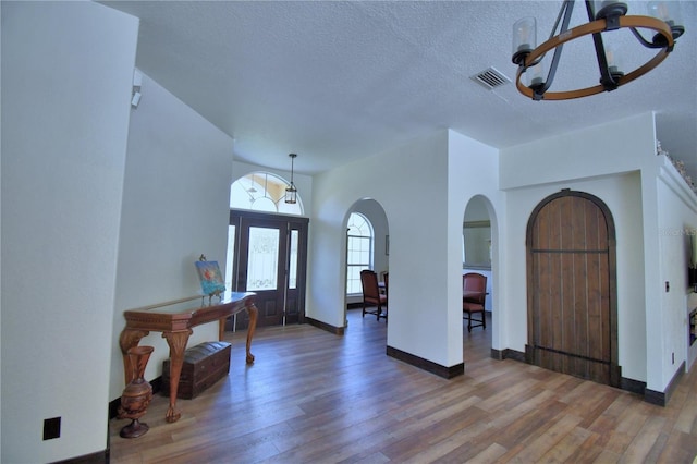 10708 Belo Horizonte Ave, Clermont, FL 34711 - foyer entrance with arched walkways, a chandelier, wood finished floors, and a textured ceiling