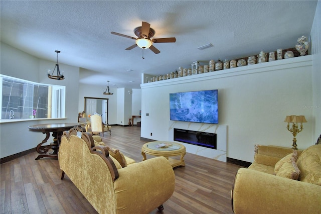 10708 Belo Horizonte Ave, Clermont, FL 34711 - living room featuring wood finished floors, a textured ceiling, a high end fireplace, ceiling fan, and a chandelier