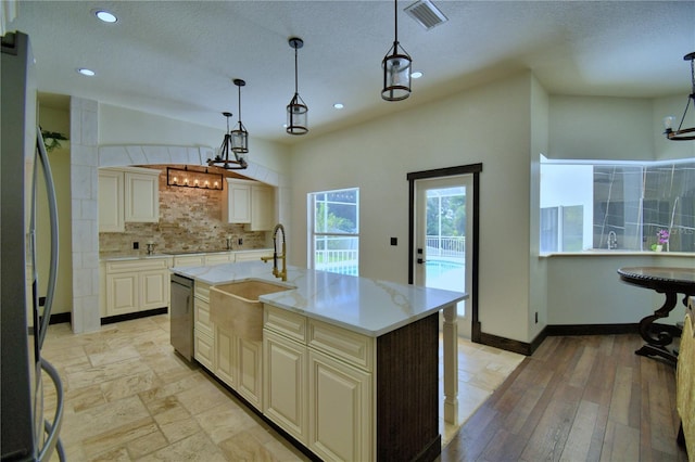 10708 Belo Horizonte Ave, Clermont, FL 34711 - kitchen featuring backsplash, stainless steel appliances, a textured ceiling, cream cabinets, and hanging light fixtures