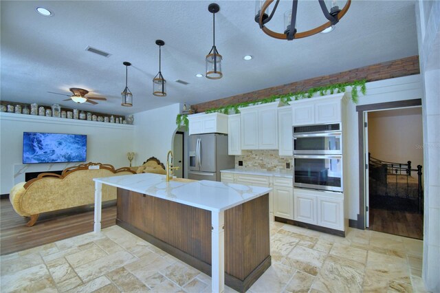 10708 Belo Horizonte Ave, Clermont, FL 34711 - kitchen featuring appliances with stainless steel finishes, white cabinets, pendant lighting, recessed lighting, and stone tile flooring