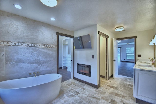 10708 Belo Horizonte Ave, Clermont, FL 34711 - bathroom featuring tile walls, a soaking tub, vanity, and recessed lighting
