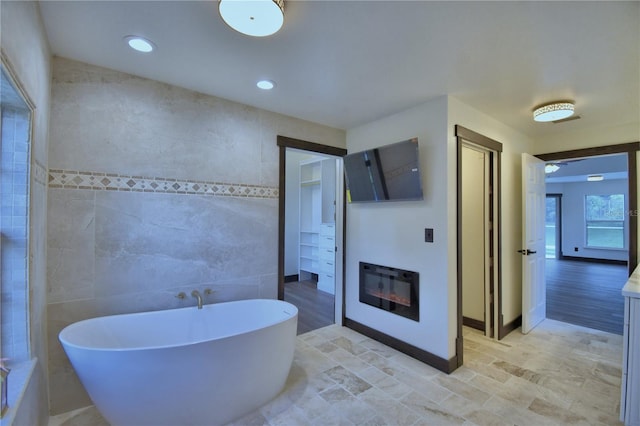 10708 Belo Horizonte Ave, Clermont, FL 34711 - full bath featuring a soaking tub, tile walls, a glass covered fireplace, vanity, and recessed lighting