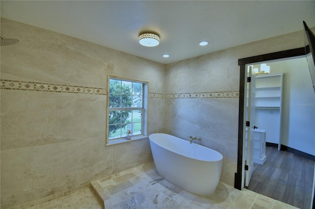 10708 Belo Horizonte Ave, Clermont, FL 34711 - bathroom with a soaking tub, wood finished floors, tile walls, and recessed lighting