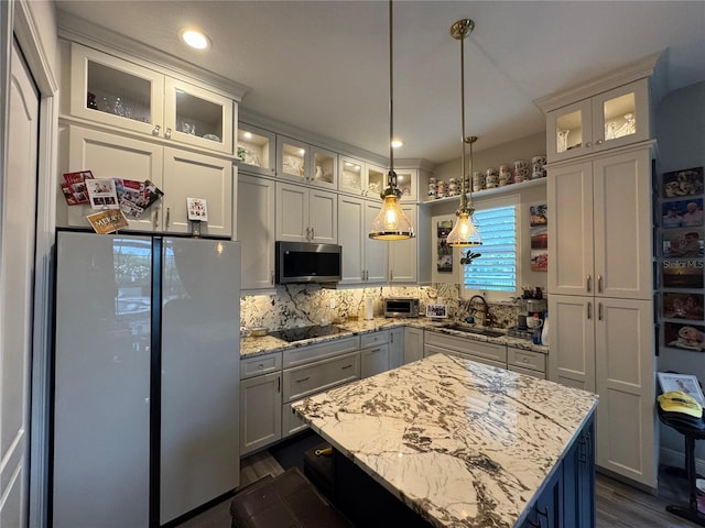 25863 Crossings Bluff Ln, Sorrento, FL 32776 - kitchen with stainless steel microwave, freestanding refrigerator, black electric cooktop, tasteful backsplash, and light stone counters