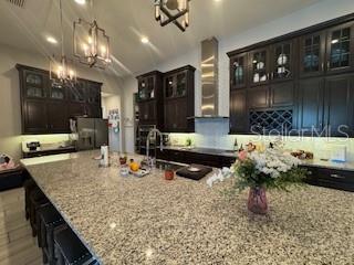 25863 Crossings Bluff Ln, Sorrento, FL 32776 - kitchen featuring a chandelier, refrigerator, a kitchen bar, light stone countertops, and recessed lighting