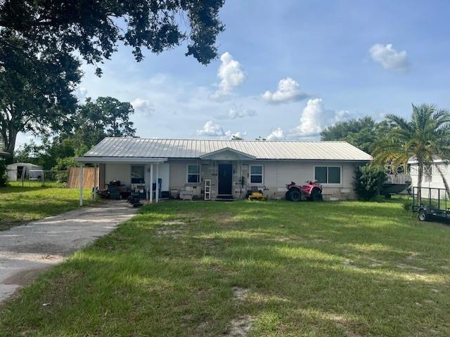 400 E Pomelo St, Lake Alfred, FL 33850 - view of front of property with a front yard, a metal roof, concrete driveway, and a carport