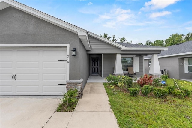 910 Blue Tide Ln, Lakeland, FL 33809 - view of exterior entry with stone siding, a garage, covered porch, driveway, and a lawn