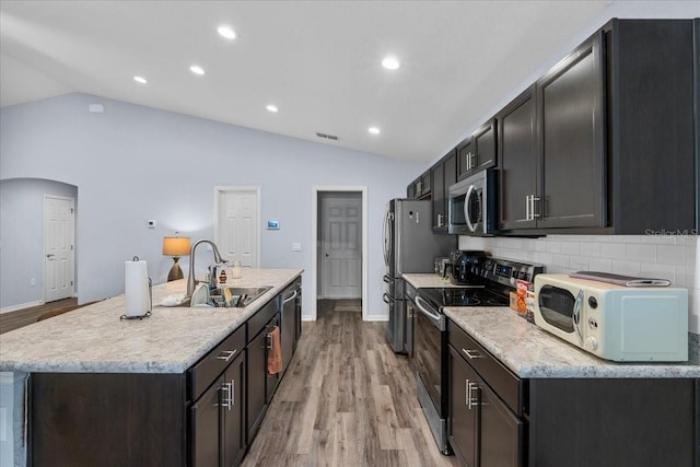 910 Blue Tide Ln, Lakeland, FL 33809 - kitchen with appliances with stainless steel finishes, lofted ceiling, light wood-style floors, tasteful backsplash, and an island with sink