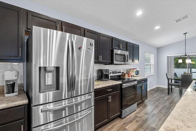 910 Blue Tide Ln, Lakeland, FL 33809 - kitchen featuring stainless steel appliances, lofted ceiling, tasteful backsplash, light countertops, and light wood-type flooring