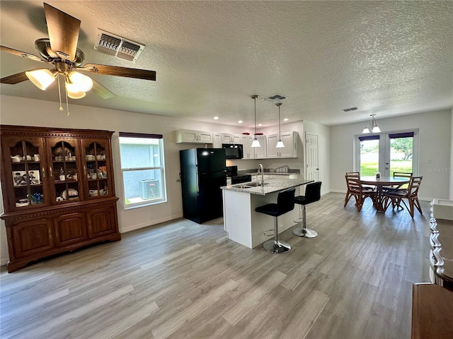1736 3rd St NE, Winter Haven, FL 33881 - kitchen with black appliances, light wood finished floors, a breakfast bar, a textured ceiling, and a ceiling fan