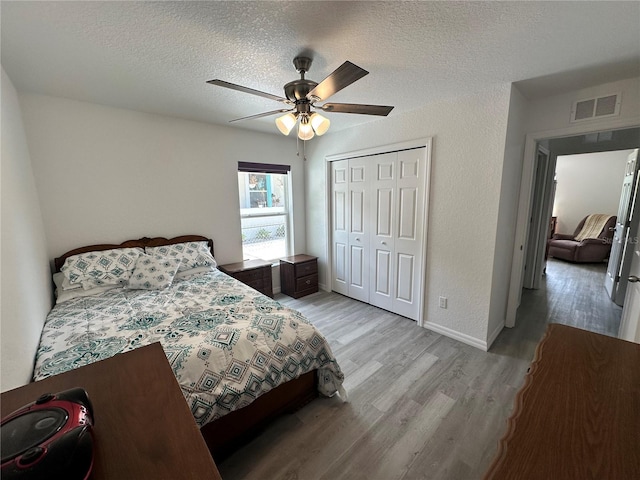 1736 3rd St NE, Winter Haven, FL 33881 - bedroom with light wood finished floors, a closet, a ceiling fan, and a textured ceiling