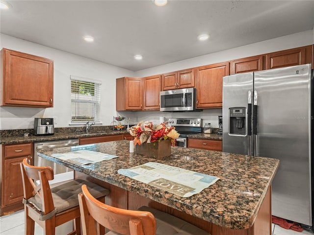 3747 Woodbury Hill Loop, Lakeland, FL 33810 - kitchen with appliances with stainless steel finishes, a breakfast bar, light tile patterned flooring, brown cabinets, and a kitchen island
