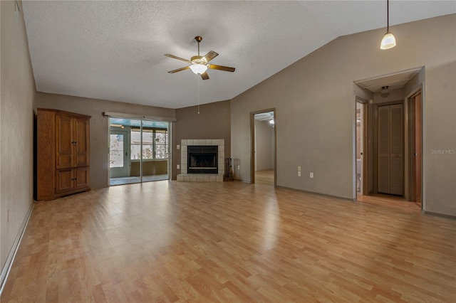 3408 Cove Ct W, Winter Haven, FL 33880 - unfurnished living room with vaulted ceiling, ceiling fan, light wood-style floors, a textured ceiling, and a fireplace