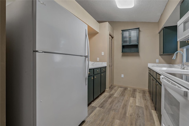 3408 Cove Ct W, Winter Haven, FL 33880 - kitchen featuring white appliances, light wood-style flooring, a textured ceiling, and light countertops