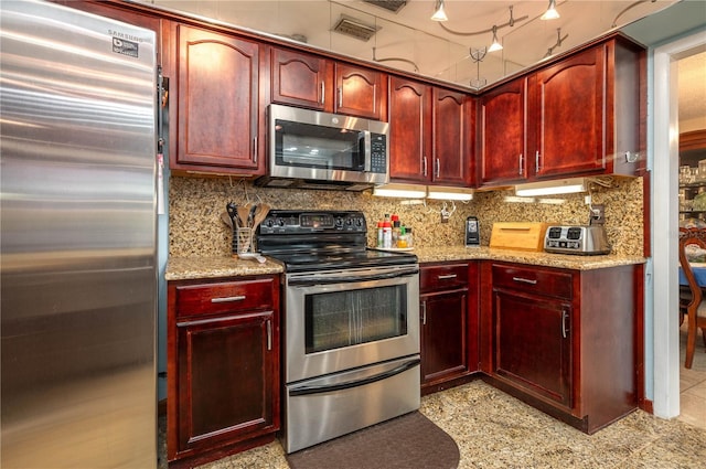 305 Hernando Rd, Winter Haven, FL 33884 - kitchen featuring appliances with stainless steel finishes, reddish brown cabinets, light stone countertops, and backsplash