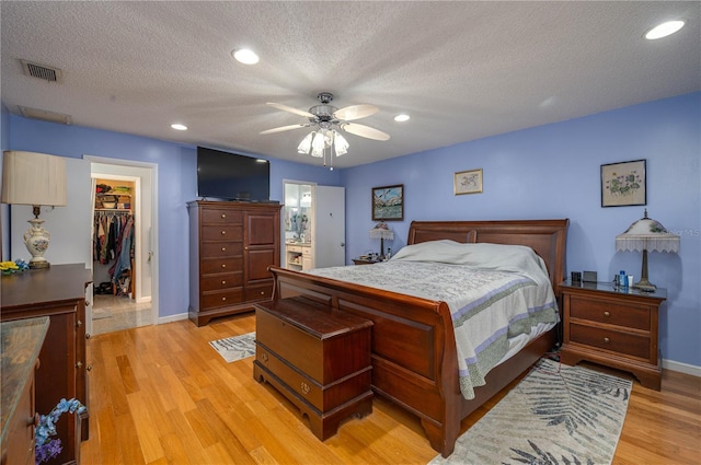 305 Hernando Rd, Winter Haven, FL 33884 - bedroom with light wood-style flooring, a walk in closet, a textured ceiling, ceiling fan, and recessed lighting