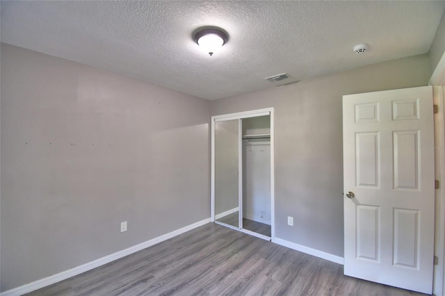 2123 Ramsdale Dr SE, Palm Bay, FL 32909 - unfurnished bedroom featuring a textured ceiling, wood finished floors, and a closet