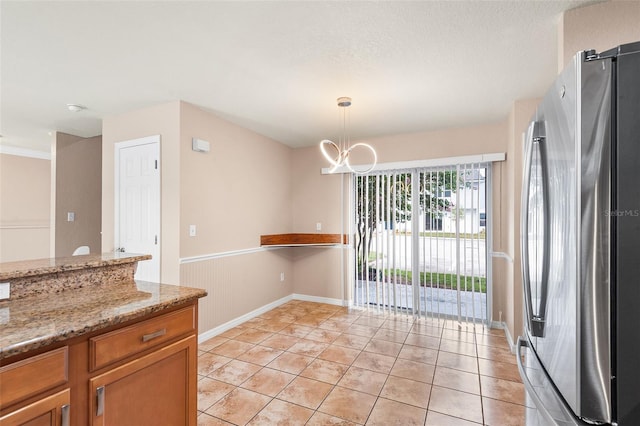 222 Carpenters Way Unit 73, Lakeland, FL 33805 - kitchen with freestanding refrigerator, light stone countertops, brown cabinets, pendant lighting, and a chandelier