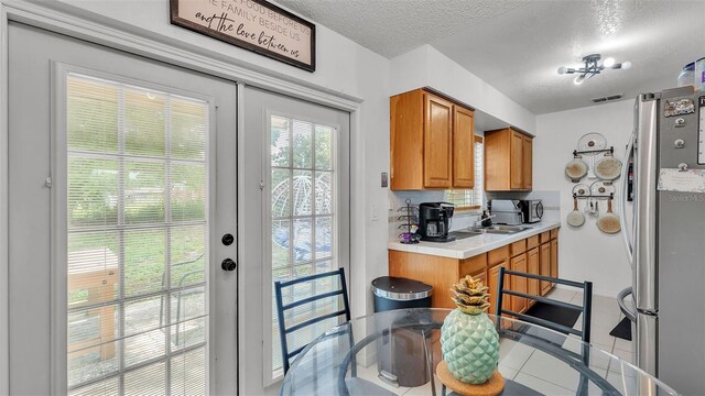 815 Everett St, Lake Alfred, FL 33850 - kitchen featuring freestanding refrigerator, light countertops, brown cabinets, tile patterned floors, and a textured ceiling