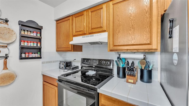 815 Everett St, Lake Alfred, FL 33850 - kitchen featuring electric range, freestanding refrigerator, under cabinet range hood, tasteful backsplash, and tile countertops