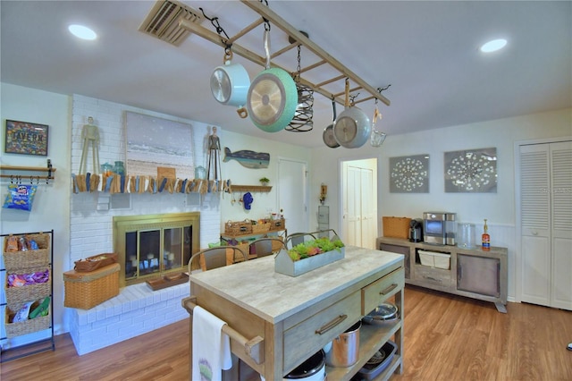 2814 Grapefruit Dr, Auburndale, FL 33823 - kitchen with wood finished floors, a brick fireplace, a warming drawer, a kitchen island, and recessed lighting