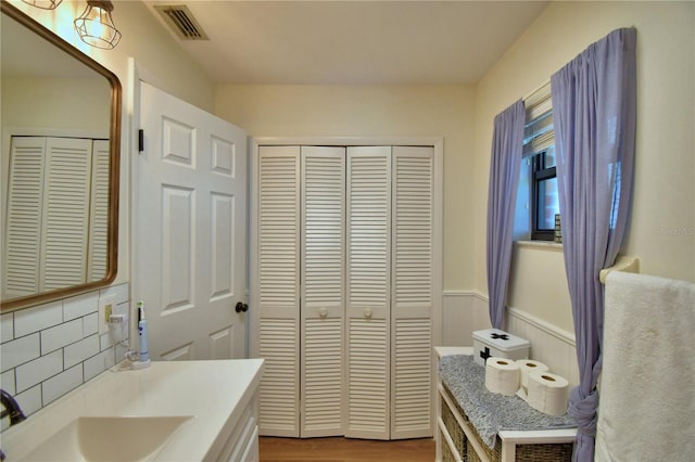 2814 Grapefruit Dr, Auburndale, FL 33823 - bathroom featuring a closet, wood finished floors, wainscoting, vanity, and tasteful backsplash