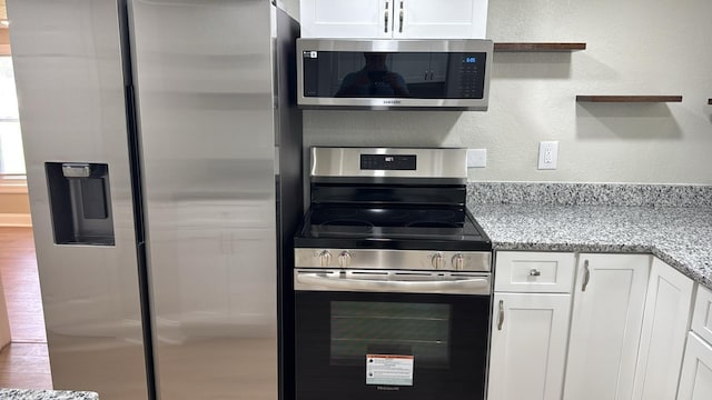 713 4th St NE, Fort Meade, FL 33841 - kitchen with appliances with stainless steel finishes, white cabinetry, a textured wall, light stone countertops, and open shelves