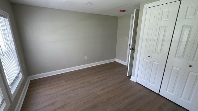 713 4th St NE, Fort Meade, FL 33841 - unfurnished bedroom with dark wood-type flooring, a closet, and a textured ceiling