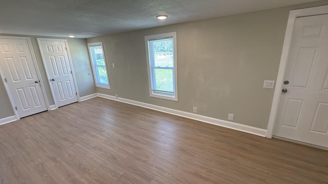 713 4th St NE, Fort Meade, FL 33841 - unfurnished bedroom featuring wood finished floors, two closets, and a textured ceiling